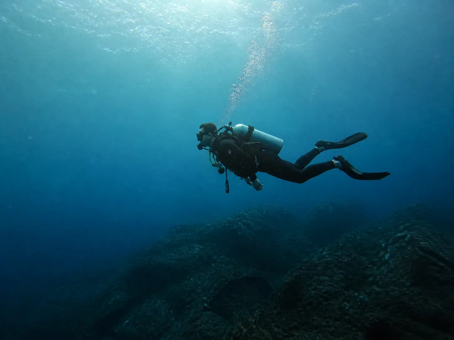 A scuba diver swimming above a rocky reef